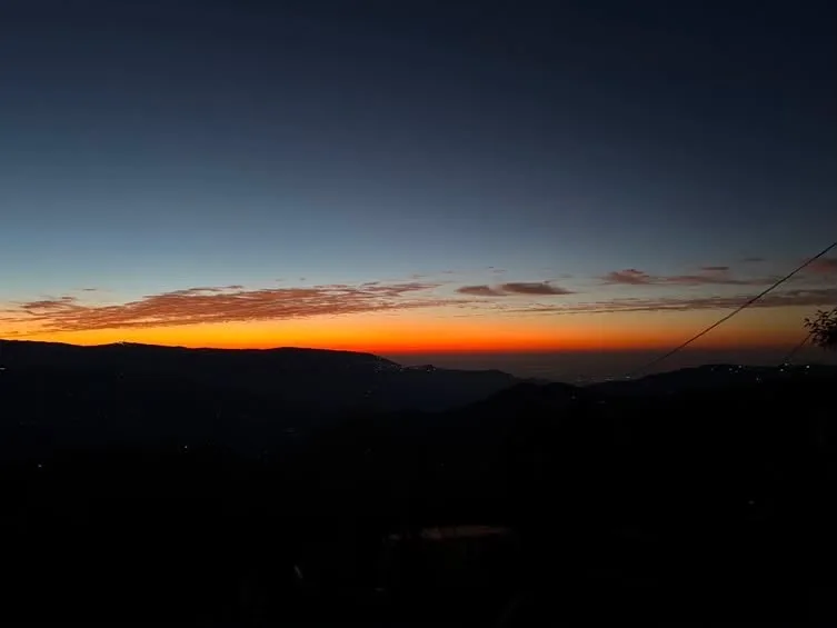 Fiery dusk horizon glow over distant hills surrounding Zambala Dwelling Nest homestay in Sukhia Pokhari