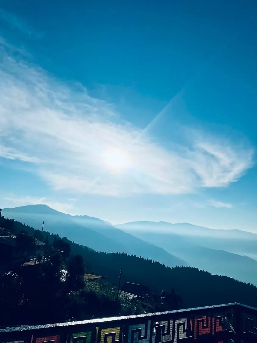 Bright morning sun rays illuminating mist-draped pine valleys from the wooden balcony of Zambala Dwelling Nest